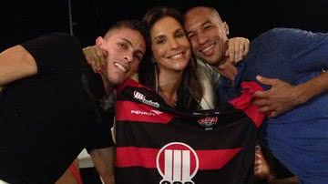 Imagem Ivete posa ao lado de jogadores do Vitória segurando a camisa do time