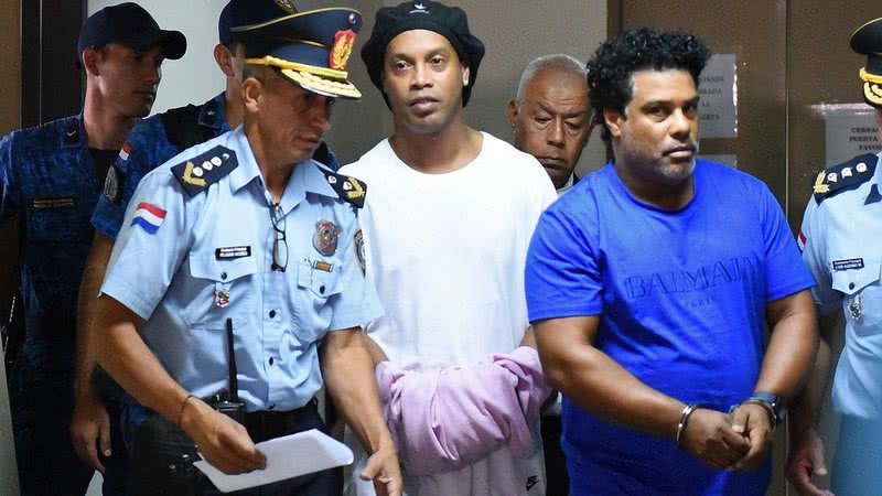 Ronaldinho e Assis sendo conduzidos por agentes da Polícia em 2020, no Paraguai (Foto: Divulgação)