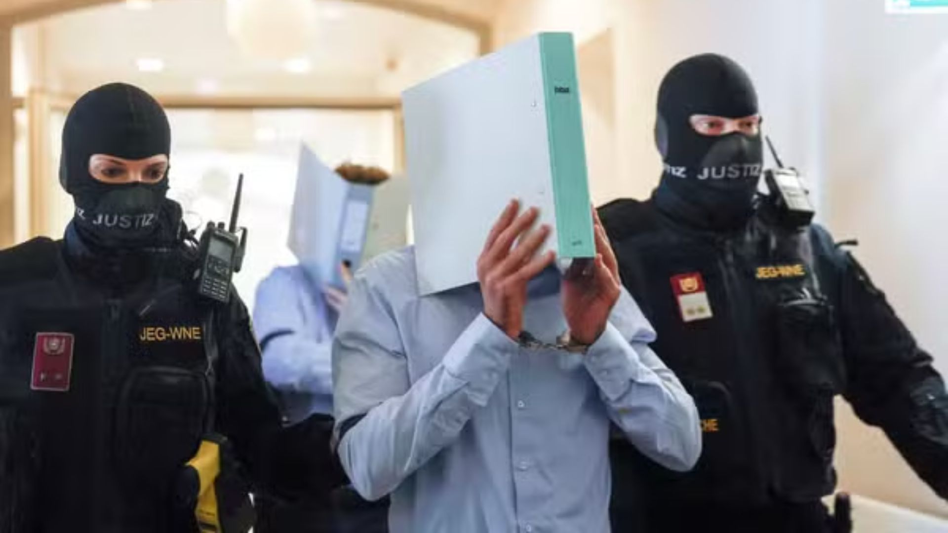 Jovem cobre o rosto com uma pasta a caminho do tribunal.