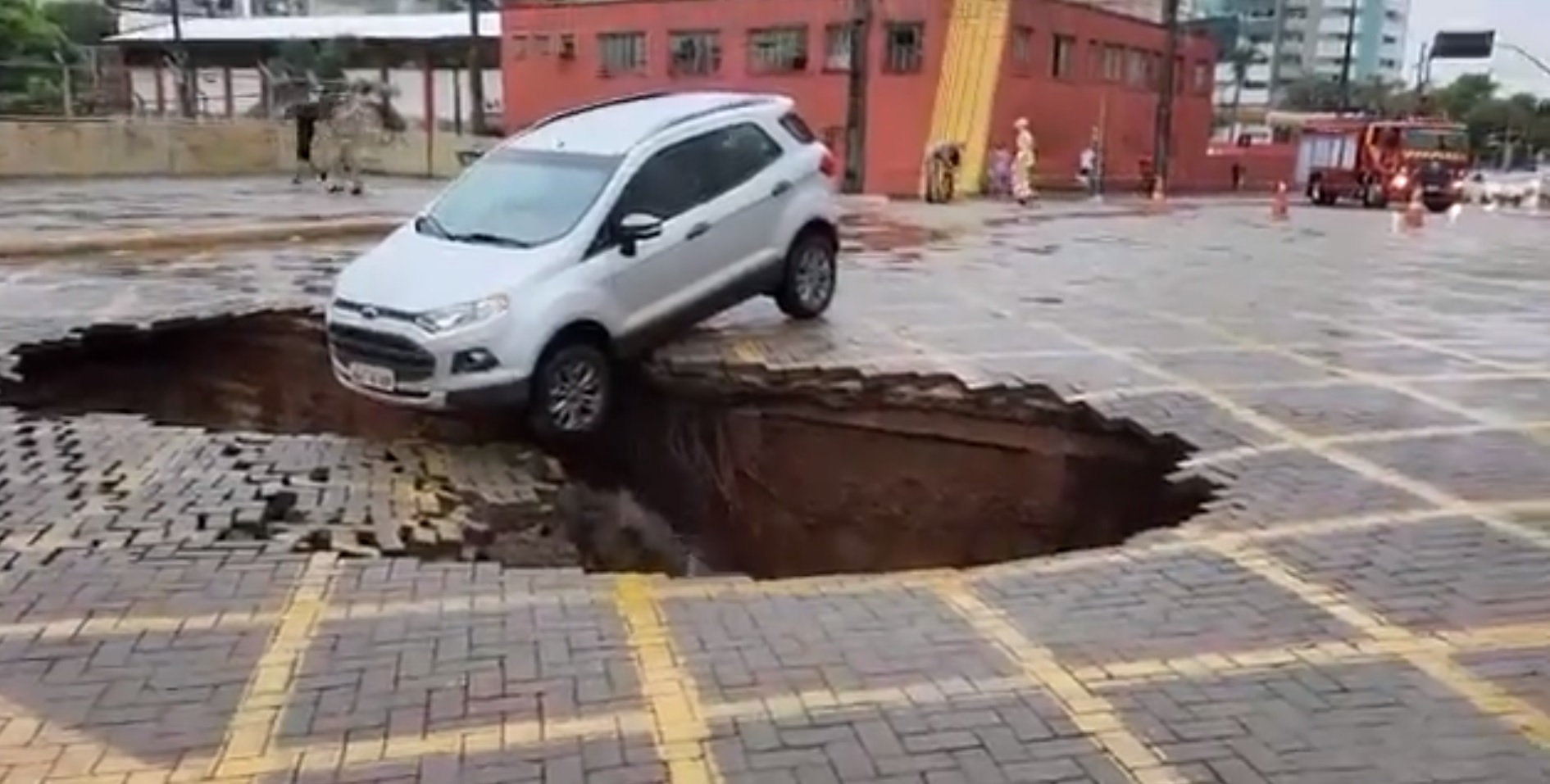 Asfalto cede em avenida e carro fica pendurado em cratera; veja vídeo