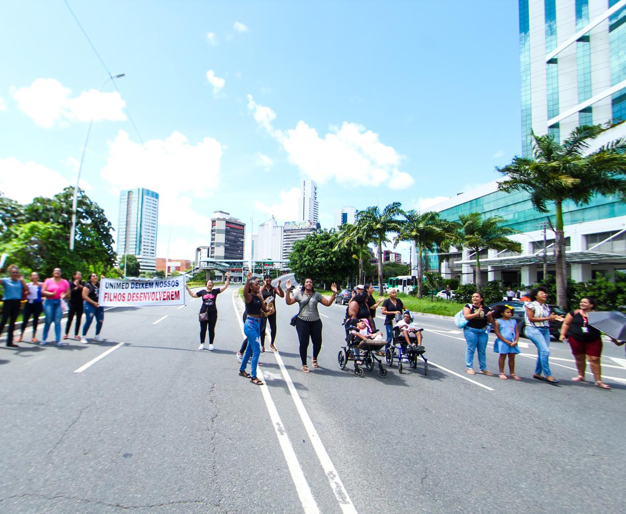 Foto das manifestantes e crianças no meio da rua protestando contra a Unimed