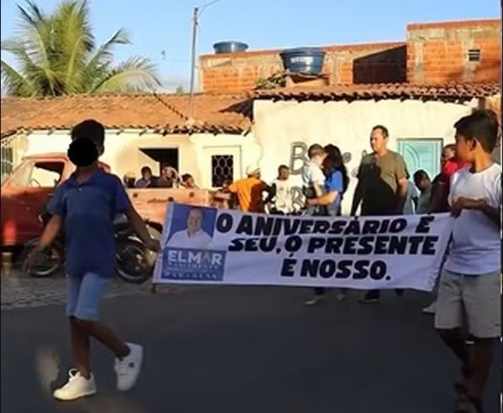 Faixa com referência ao aniversário de Elmar foi carregada em evento de inauguração de rodovia na Bahia — Foto: Reprodução/Redes sociais