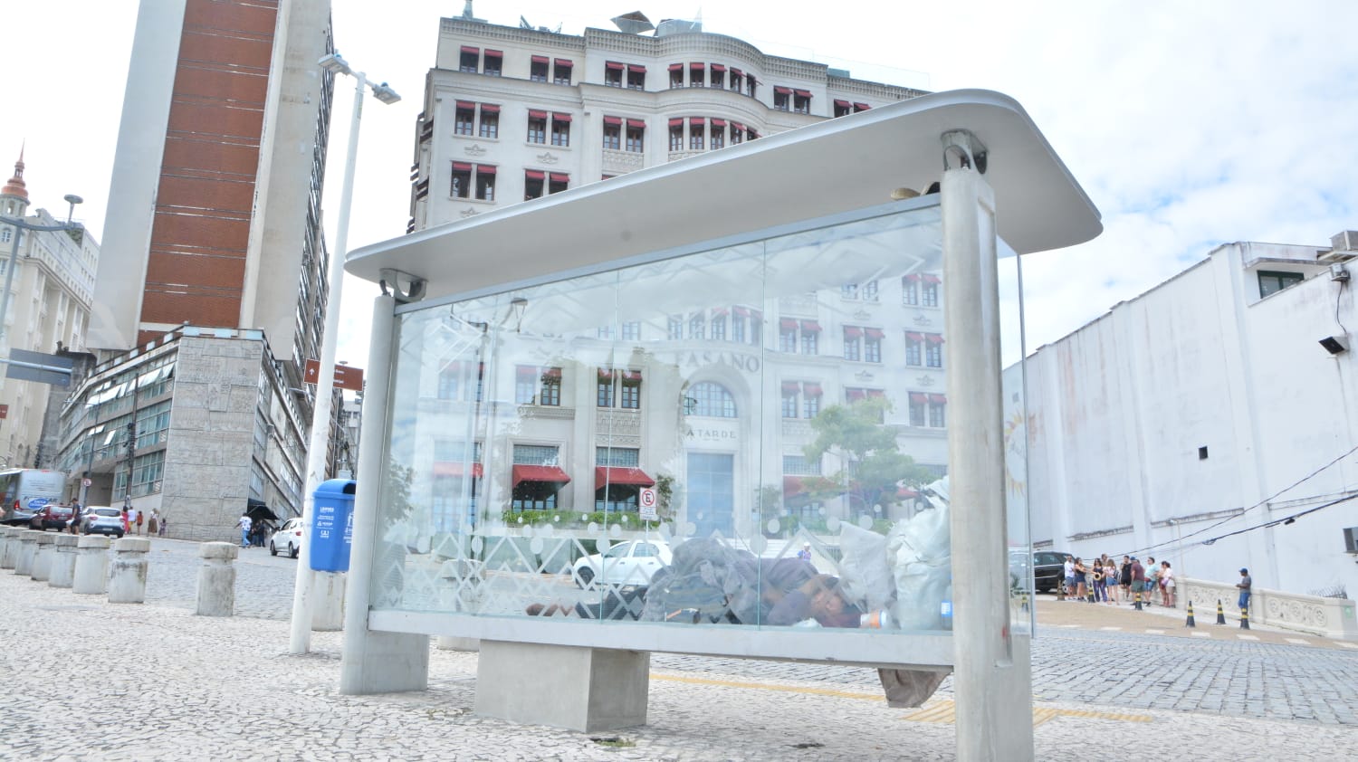 Homem dorme no ponto de ônibus em frente a hotel 