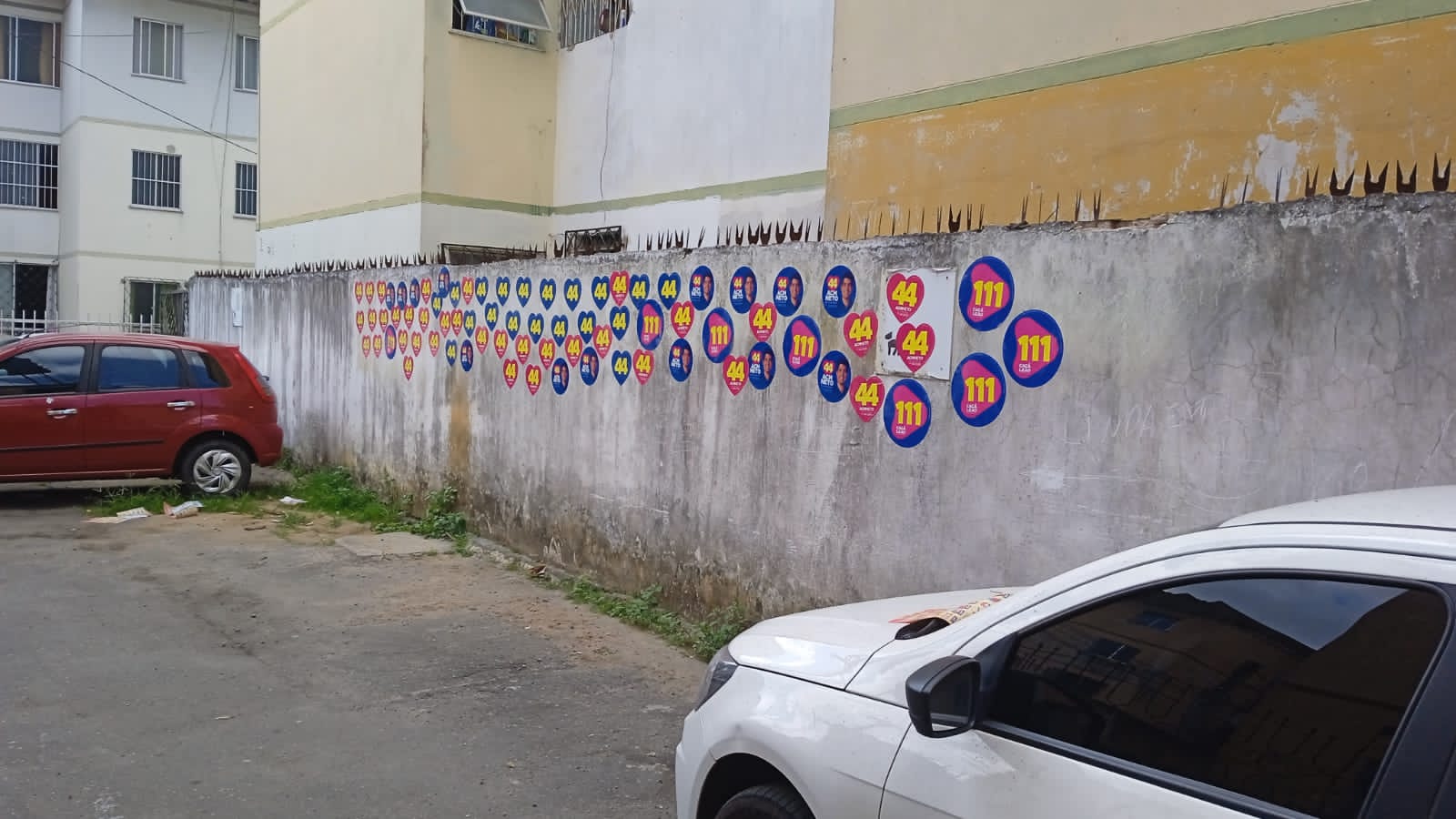 Muros de condomínio em Salvador "pichados" com adesivos das campanhas de ACM Neto e Cacá Leão (Foto: Leitor BNews)